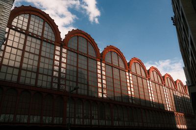 Exterior view of the facade of Antwerp Central Station in Belgium, showing large arched windows and architectural details under a blue sky.