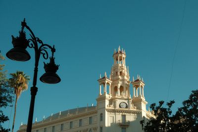A dark detailed lampost contrasting with the sun hitting the Casa Del Chavo building.