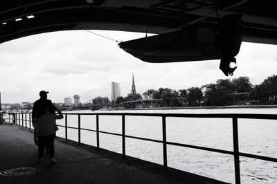 Black and white street photo of a father and son under riverside overpass in Frankfurt, in the distance looking at the ECB building.